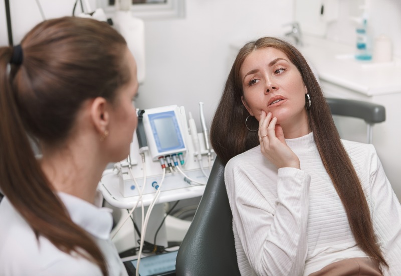 A Woman with tooth pain consulting dentist in a clinic for emergency dentistry in Monroeville, PA