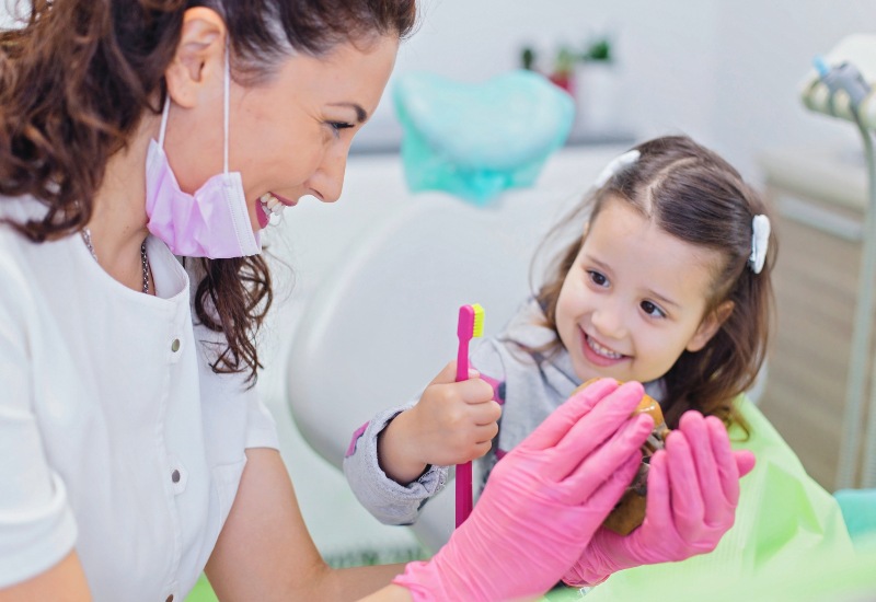 A Smiling girl learns oral hygiene from a dentist during her first visit in Monroeville, PA