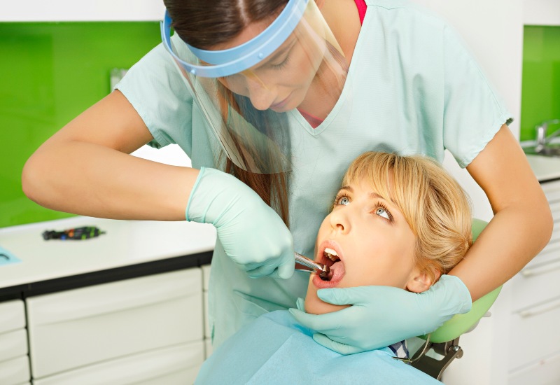 A dentist performing a tooth extraction for a patient in a dental office in Monroeville, PA
