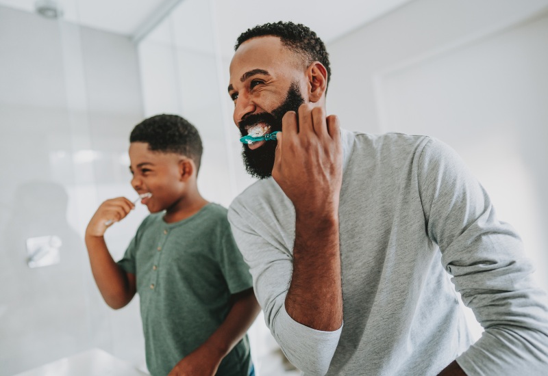 A father sharing facts about fluoride while brushing teeth with his son in Monroeville, PA