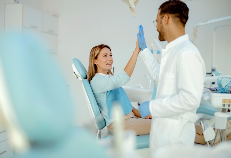 A smiling patient & dentist high-fiving after a check-up, promoting preventative care in Monroeville