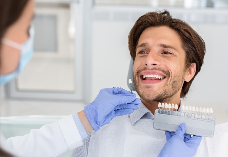A dental professional performing shade matching for a smile makeover in Monroeville, PA